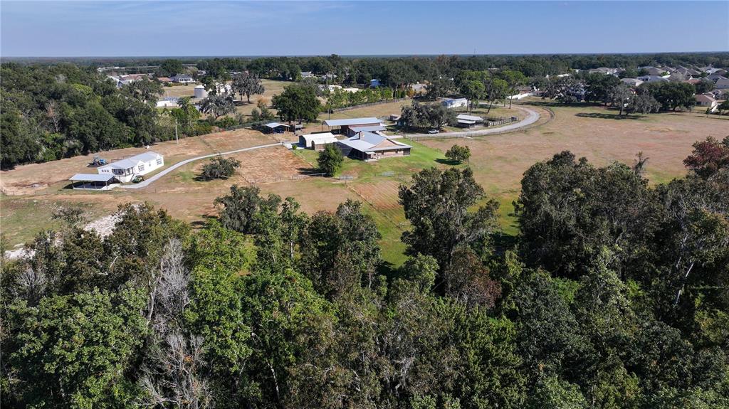An aerial view shows a rural property with multiple buildings, a driveway, and surrounding trees — 3182 INDIAN RIDGE PLACE, LAKELAND, FL