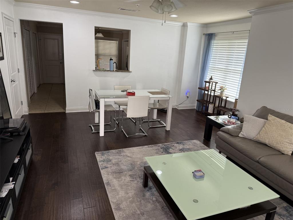 A living and dining area features dark wood floors, white walls, and a glass-topped table — 4639 SW 48TH DRIVE UNIT 149, GAINESVILLE, FL