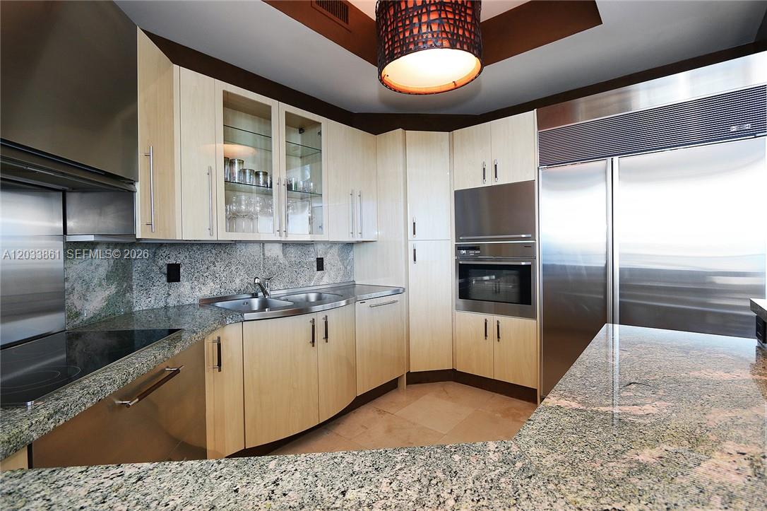 A modern kitchen features light wood cabinets, granite countertops, and stainless steel appliances — 100 S Pointe Dr # 601, Miami Beach FL 33139, MIAMI BEACH, FL