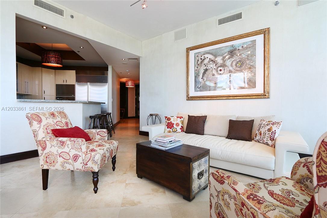 A living room features a white sofa, two patterned armchairs, and a wooden coffee table — 100 S Pointe Dr # 601, Miami Beach FL 33139, MIAMI BEACH, FL