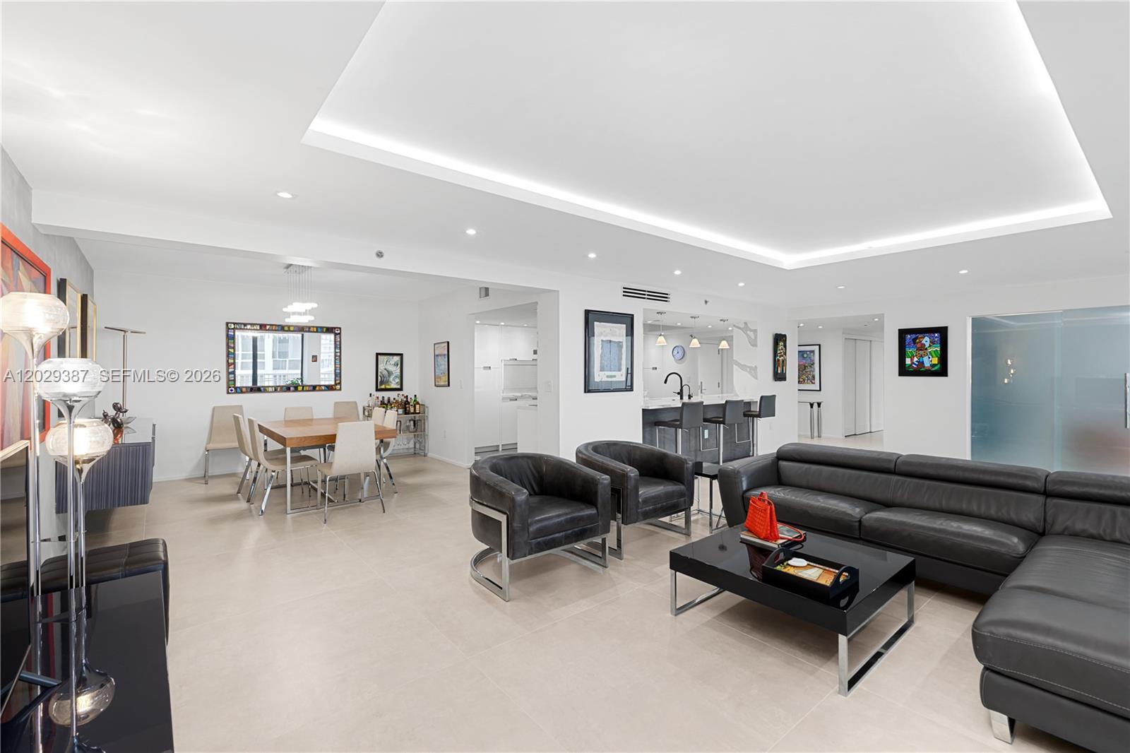 A modern, open-concept living and dining area features white walls, tile floors, and leather furniture — 10205 Collins Ave # 604, Bal Harbour FL 33154, BAL HARBOUR, FL