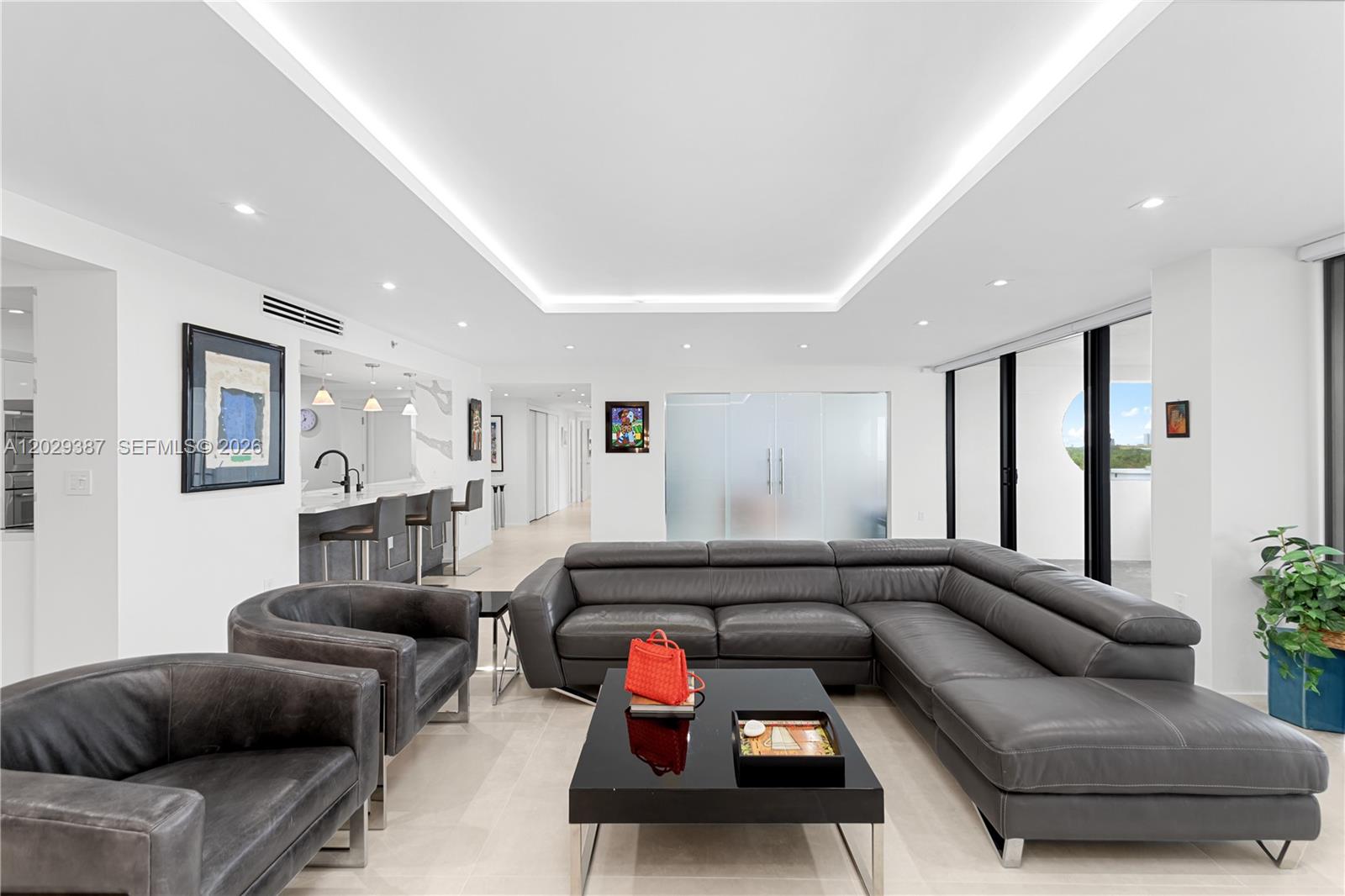 A modern living room features a large grey sectional, leather armchairs, and a black coffee table — 10205 Collins Ave # 604, Bal Harbour FL 33154, BAL HARBOUR, FL