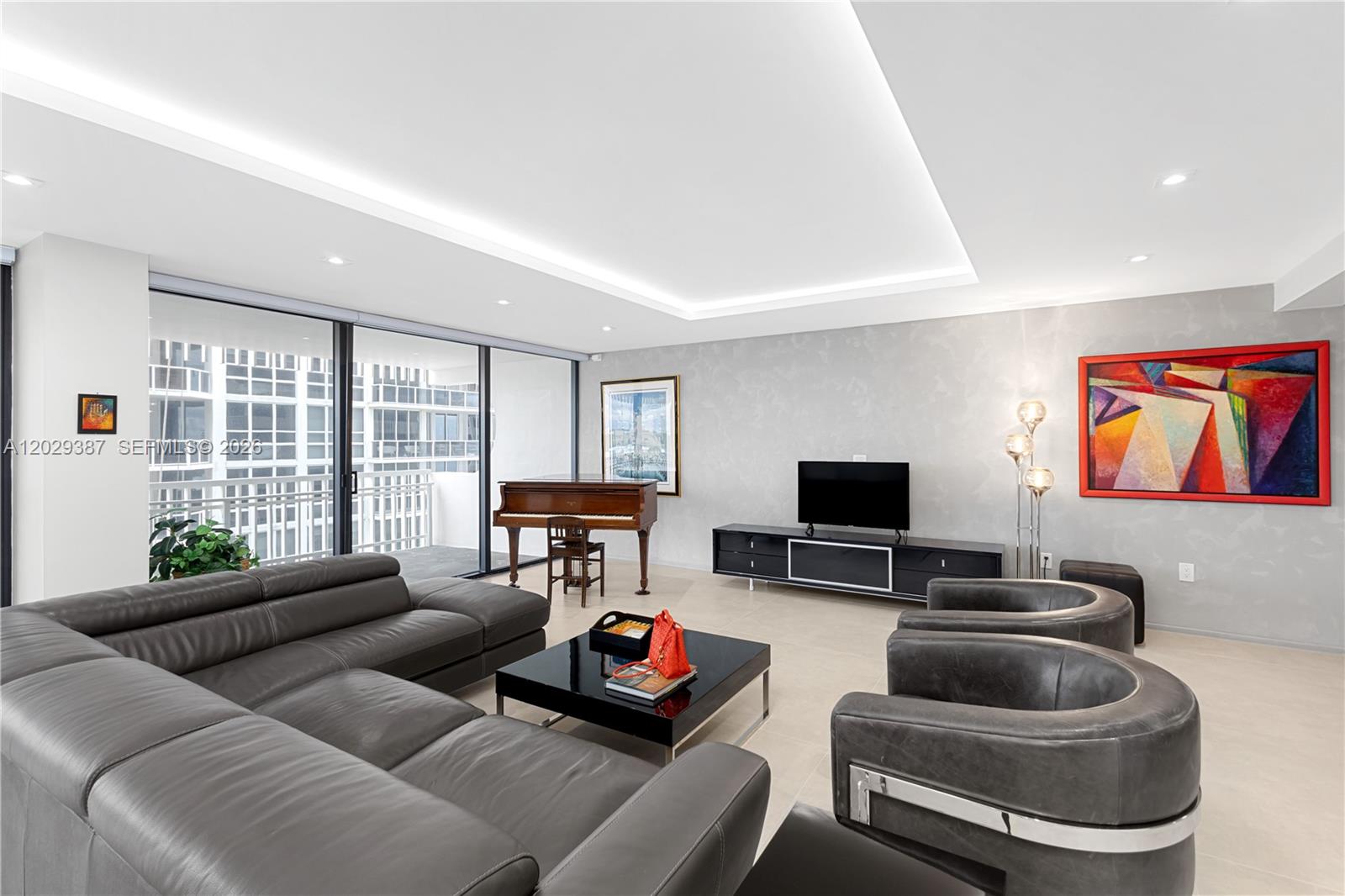 A modern living room features a large grey sectional, two armchairs, and a grand piano — 10205 Collins Ave # 604, Bal Harbour FL 33154, BAL HARBOUR, FL