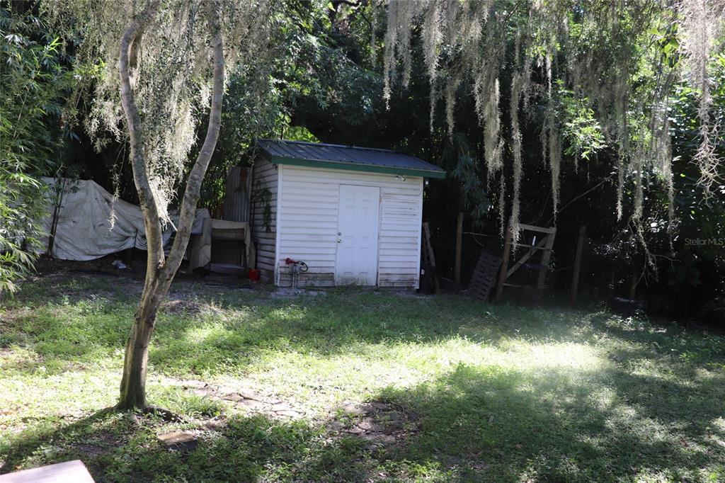 A white storage shed sits in a grassy backyard surrounded by trees with hanging moss — 14150 NE 110TH AVENUE ROAD, FORT MC COY, FL