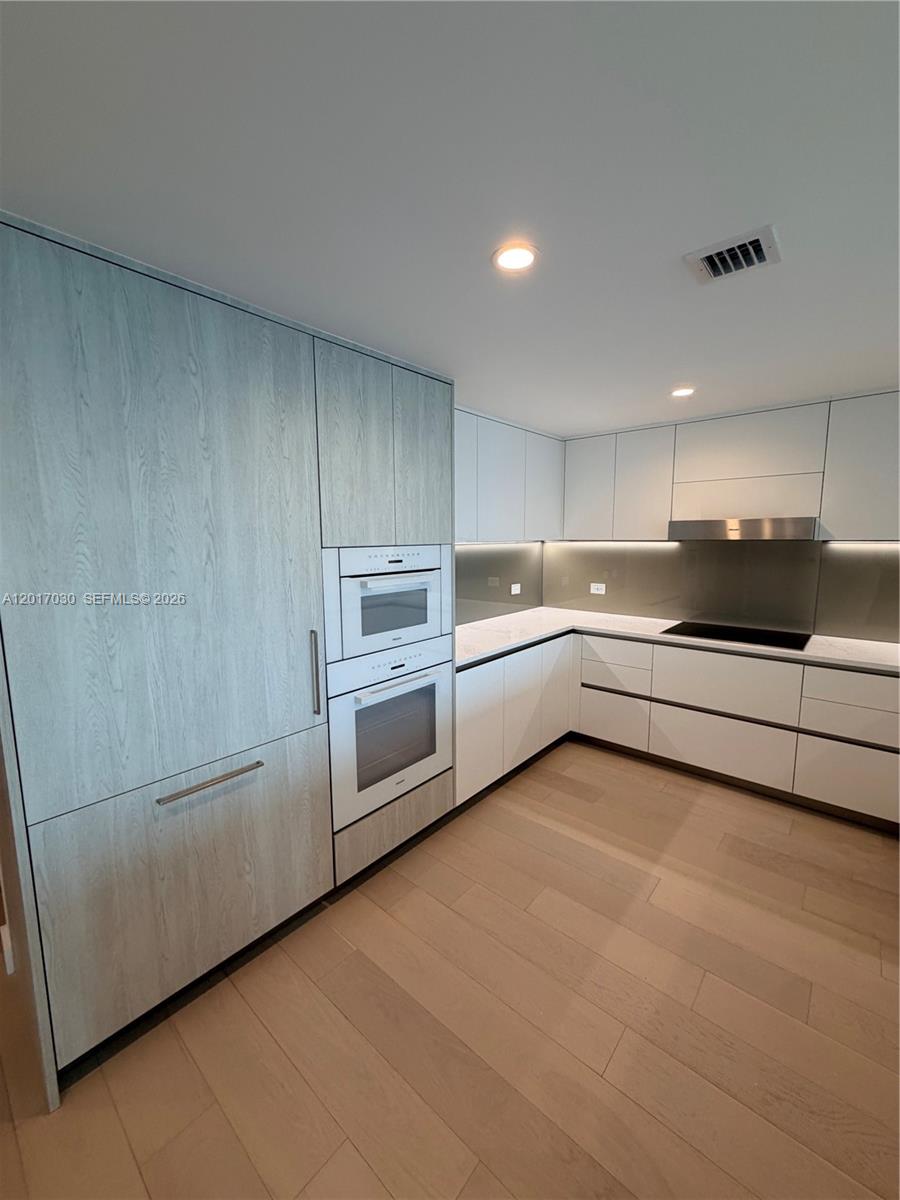 A modern kitchen features light wood cabinetry, white flat-panel cabinets, and stainless steel appliances — 9221 E Bay Harbor Dr # 309, Bay Harbor Islands FL 33154, BAY HARBOR ISLANDS, FL