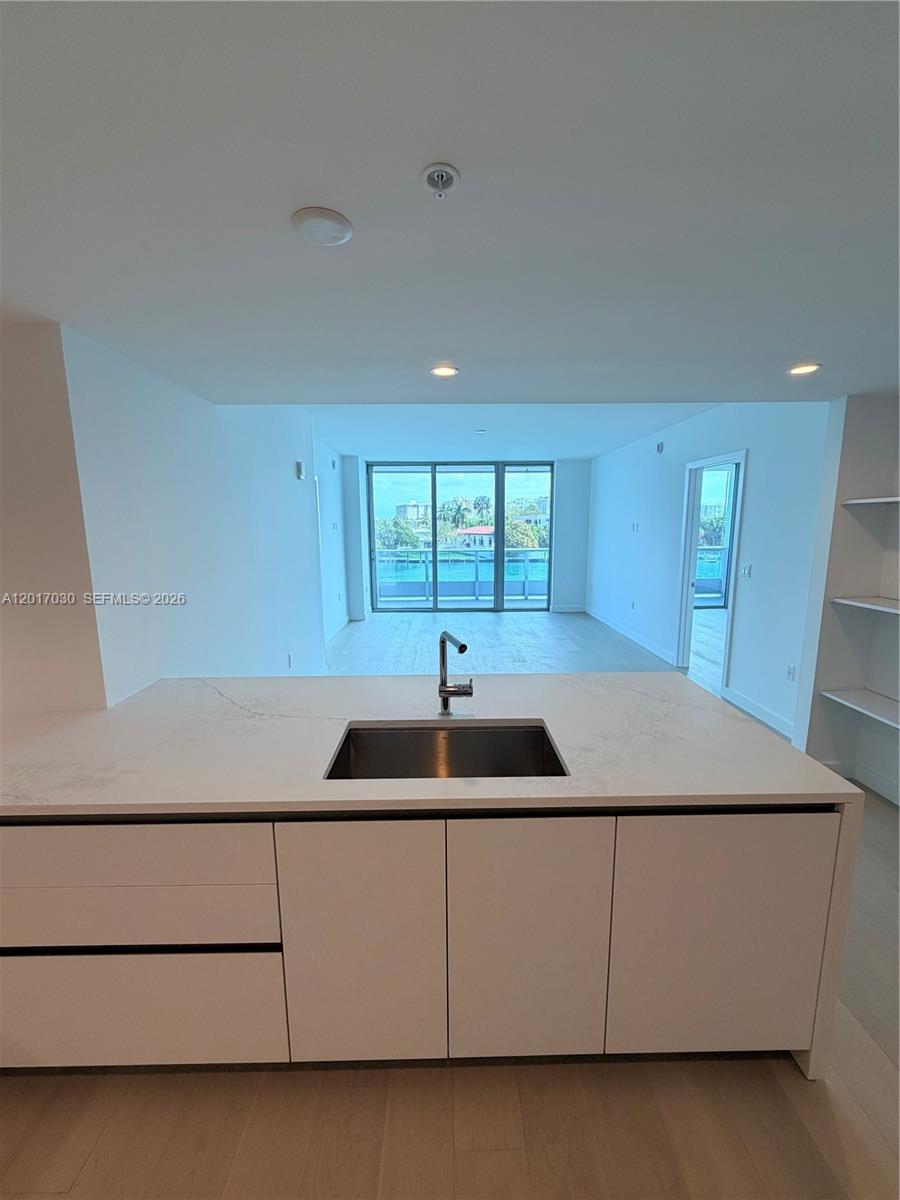 A kitchen island with a white countertop and sink overlooks an open living area — 9221 E Bay Harbor Dr # 309, Bay Harbor Islands FL 33154, BAY HARBOR ISLANDS, FL