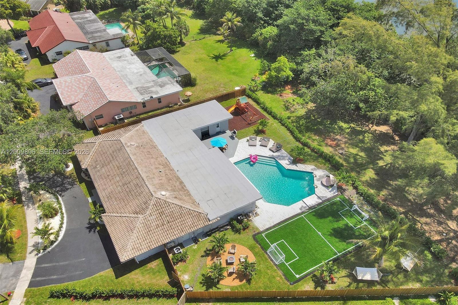 An aerial view shows a house with a pool, soccer field, and fire pit area — 1960 SW 51st Ter, Plantation FL 33317, PLANTATION, FL
