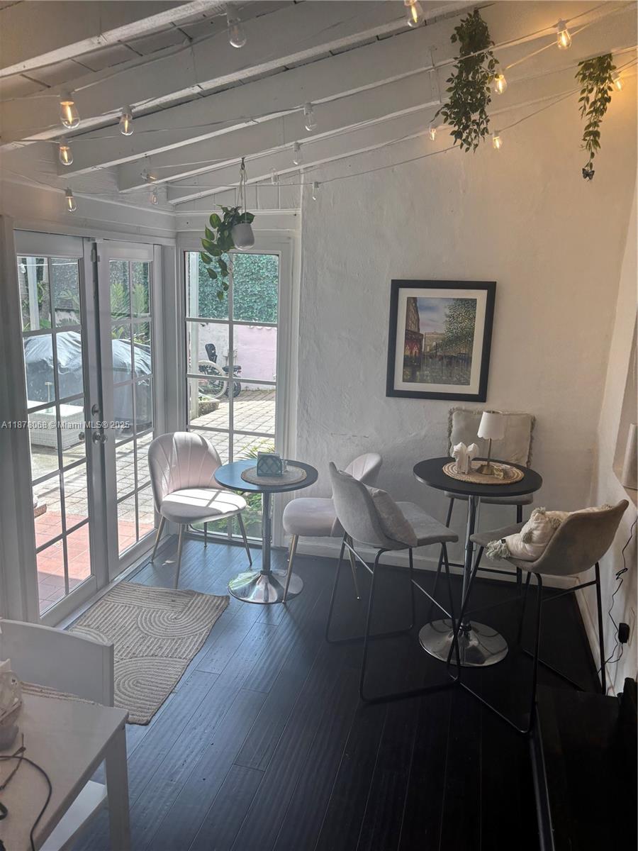 A sunroom features dark wood floors, white walls, string lights, and two small dining sets — 1239 Alton Rd # 3, Miami Beach FL 33139, MIAMI BEACH, FL