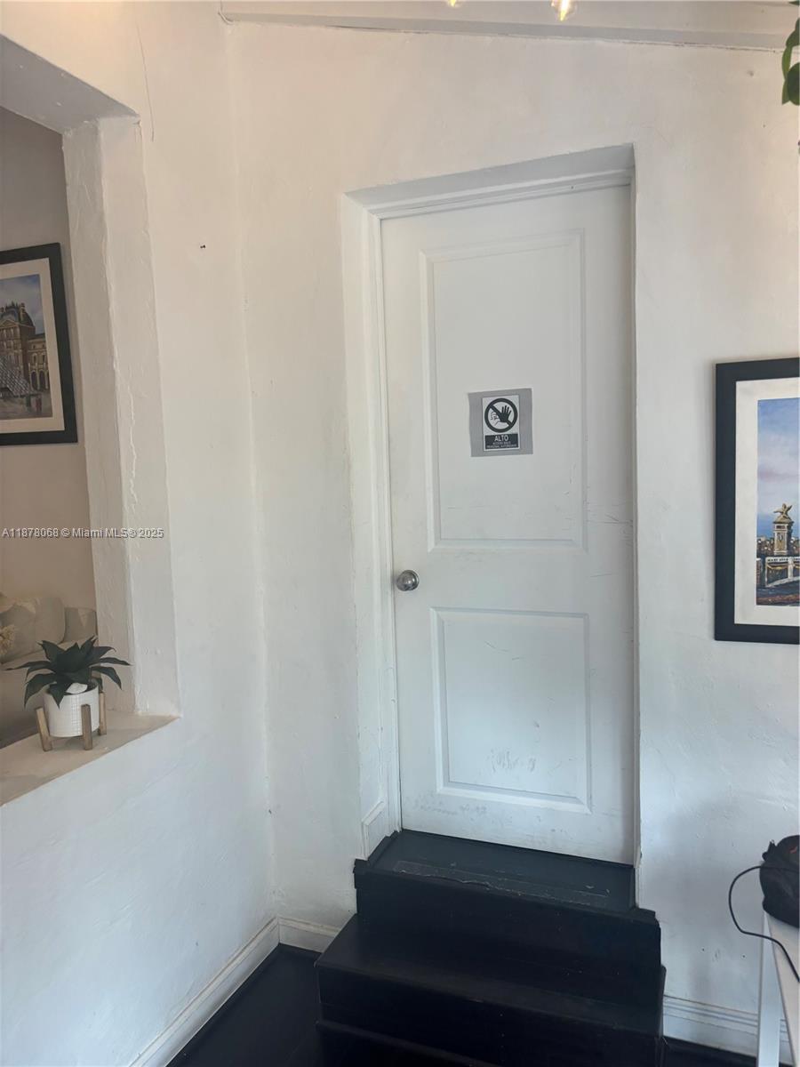 A white door with a warning sign sits above two black steps in a room — 1239 Alton Rd # 3, Miami Beach FL 33139, MIAMI BEACH, FL