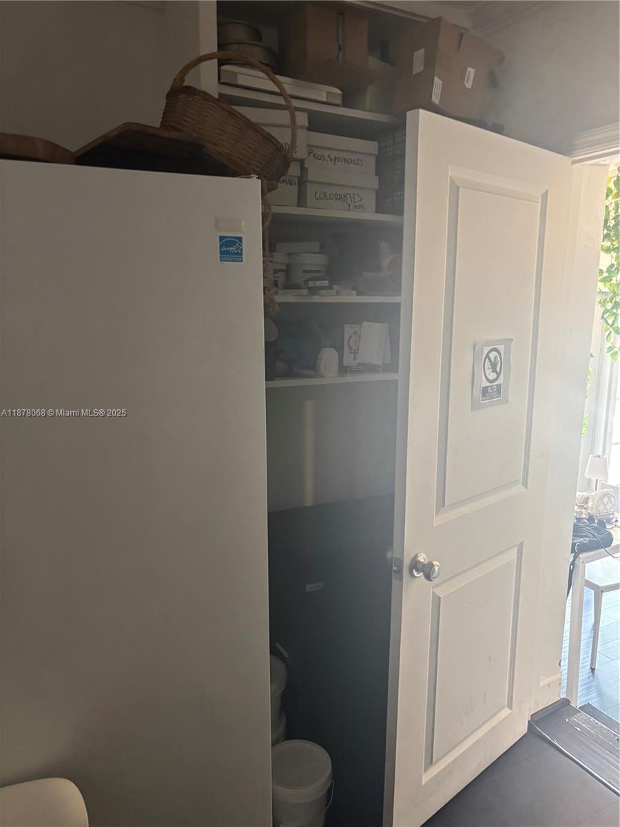 A white door opens to a pantry closet with shelves holding various boxes and supplies — 1239 Alton Rd # 3, Miami Beach FL 33139, MIAMI BEACH, FL