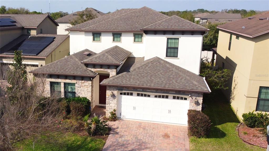 An aerial view of a two-story suburban house with a stone facade and attached garage — 5115 TIBER WAY, ST CLOUD, FL