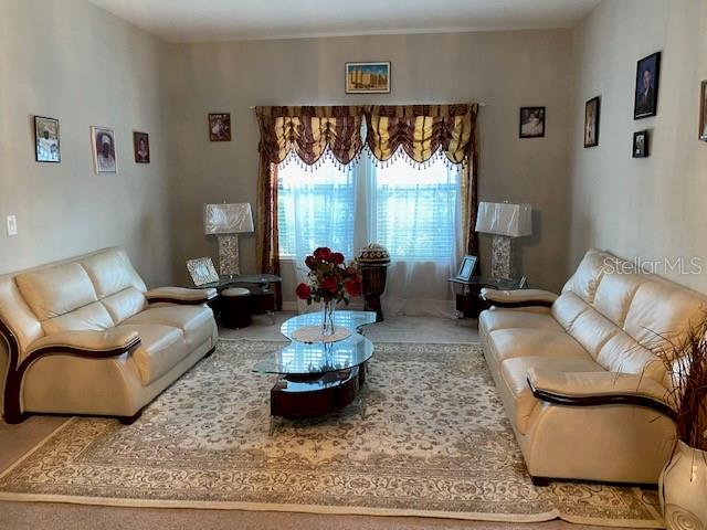 A living room features two cream-colored leather sofas, a glass coffee table, and window valances — 5115 TIBER WAY, ST CLOUD, FL