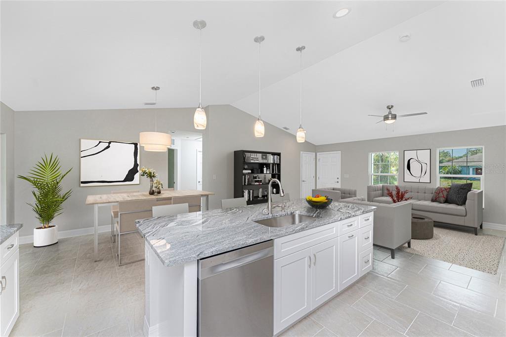 A kitchen with a granite island and stainless steel appliances overlooks a dining and living area — 1425 LINDSAY AVENUE, NORTH PORT, FL