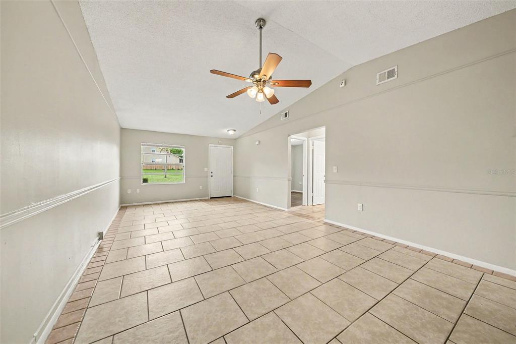 A living room with light-colored tile flooring, a vaulted ceiling, and a ceiling fan — 1188 WOODMAN WAY, ORLANDO, FL