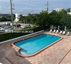 An outdoor swimming pool is surrounded by a brick patio and lounge chairs — 6450 Collins Ave # 206, Miami Beach FL 33141, MIAMI BEACH, FL