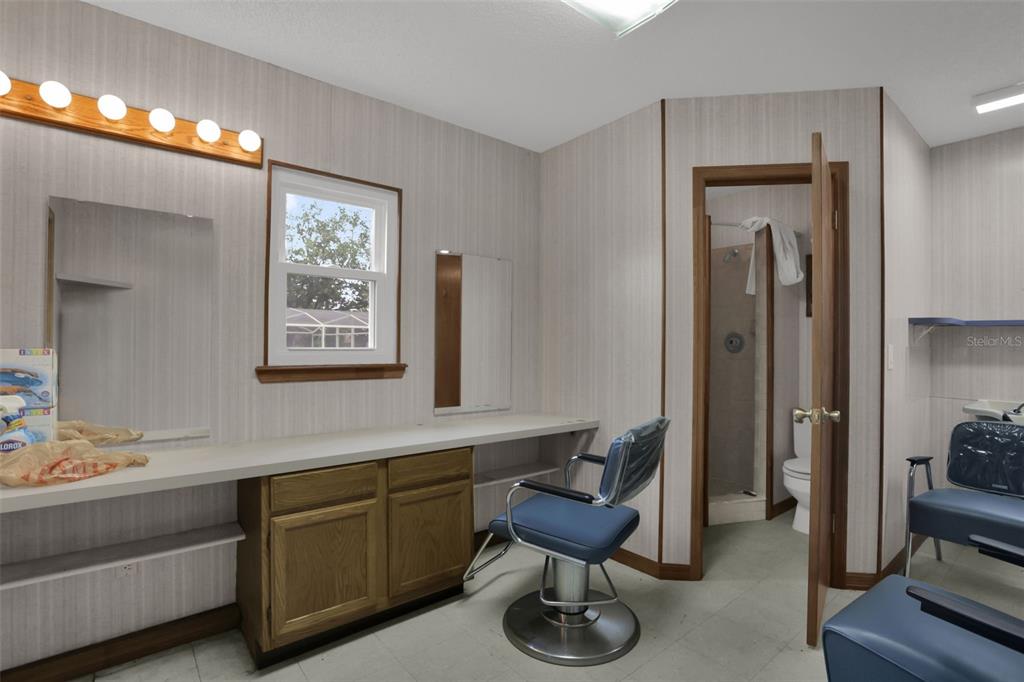 A room set up as a salon with vanity mirrors, lighting, and blue styling chairs — 1762 HOWLAND BOULEVARD, DELTONA, FL