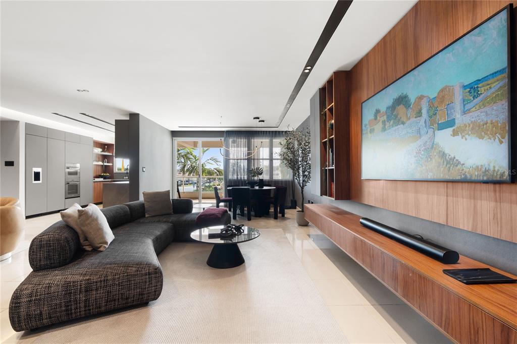 A modern living room features a curved sofa, wood-paneled media wall, and an adjacent dining area — 592 TTE CESAR GONALEZ AVE, TORRE CIBELES, TORRE I AVENUE UNIT 213, SAN JUAN, PR