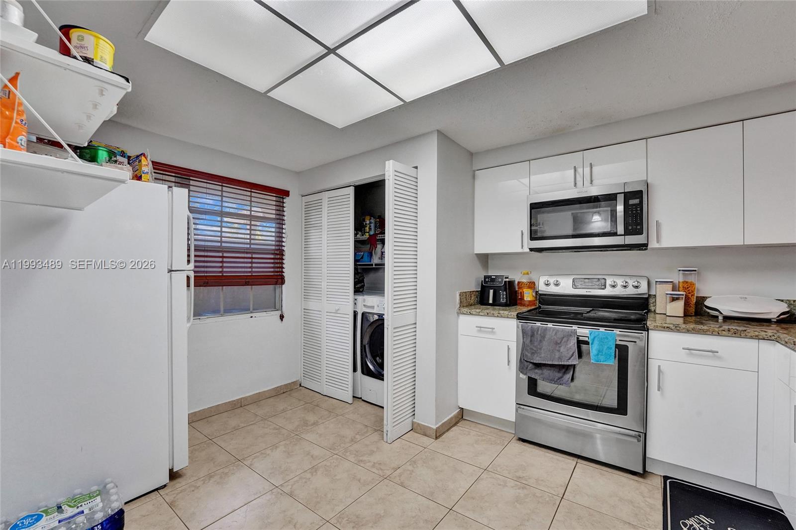 A kitchen features white cabinets, stainless steel appliances, tile flooring, and an in-unit laundry closet — 3592 NW 83rd Ln, Sunrise FL 33351, SUNRISE, FL