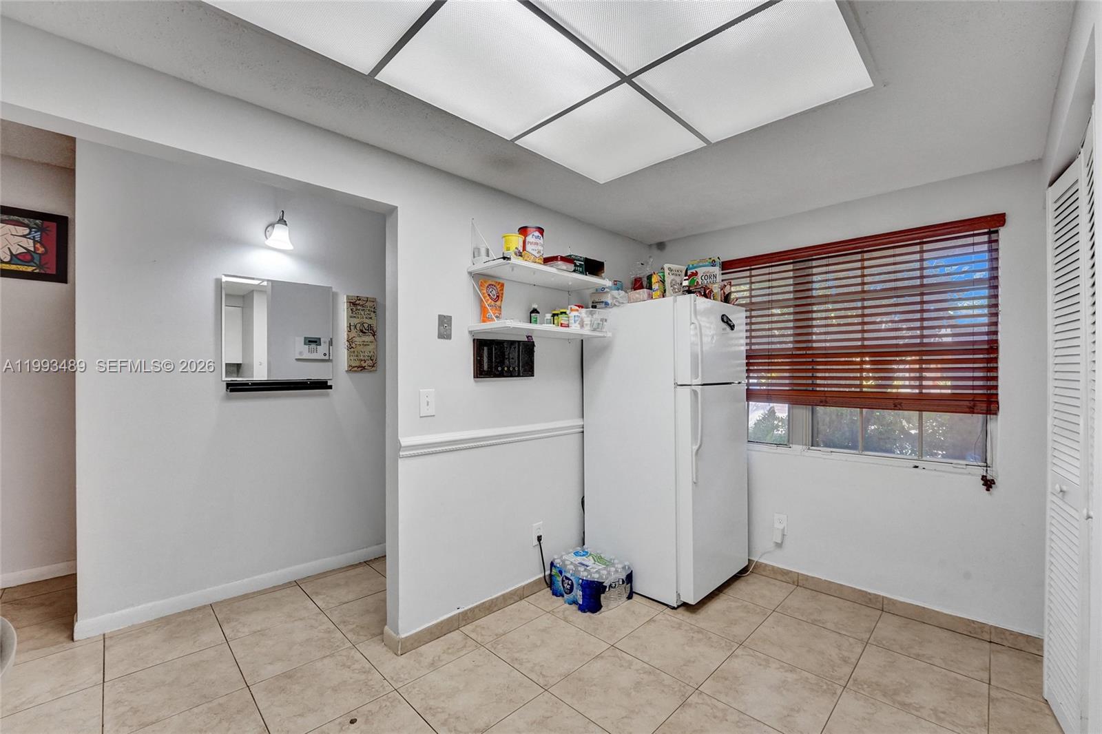 A kitchen area features a white refrigerator, open shelving, tile flooring, and a window — 3592 NW 83rd Ln, Sunrise FL 33351, SUNRISE, FL