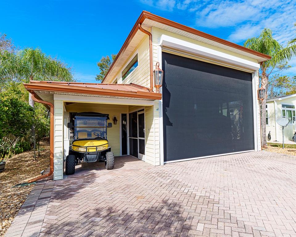 A yellow two-story garage with a covered carport, a golf cart, and a paved driveway — 6841 AMANDA VISTA CIRCLE, LAND O LAKES, FL