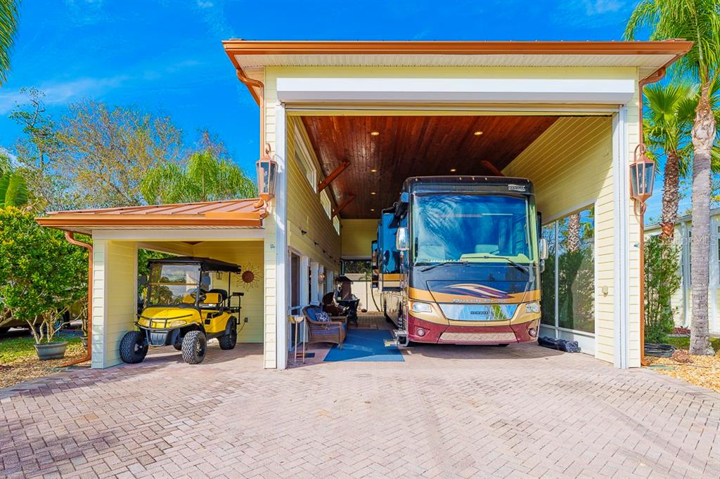 A large covered carport houses a motorhome and a golf cart on a paved driveway — 6841 AMANDA VISTA CIRCLE, LAND O LAKES, FL