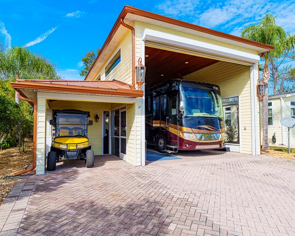 A yellow house features a large RV garage and an attached carport with a golf cart — 6841 AMANDA VISTA CIRCLE, LAND O LAKES, FL
