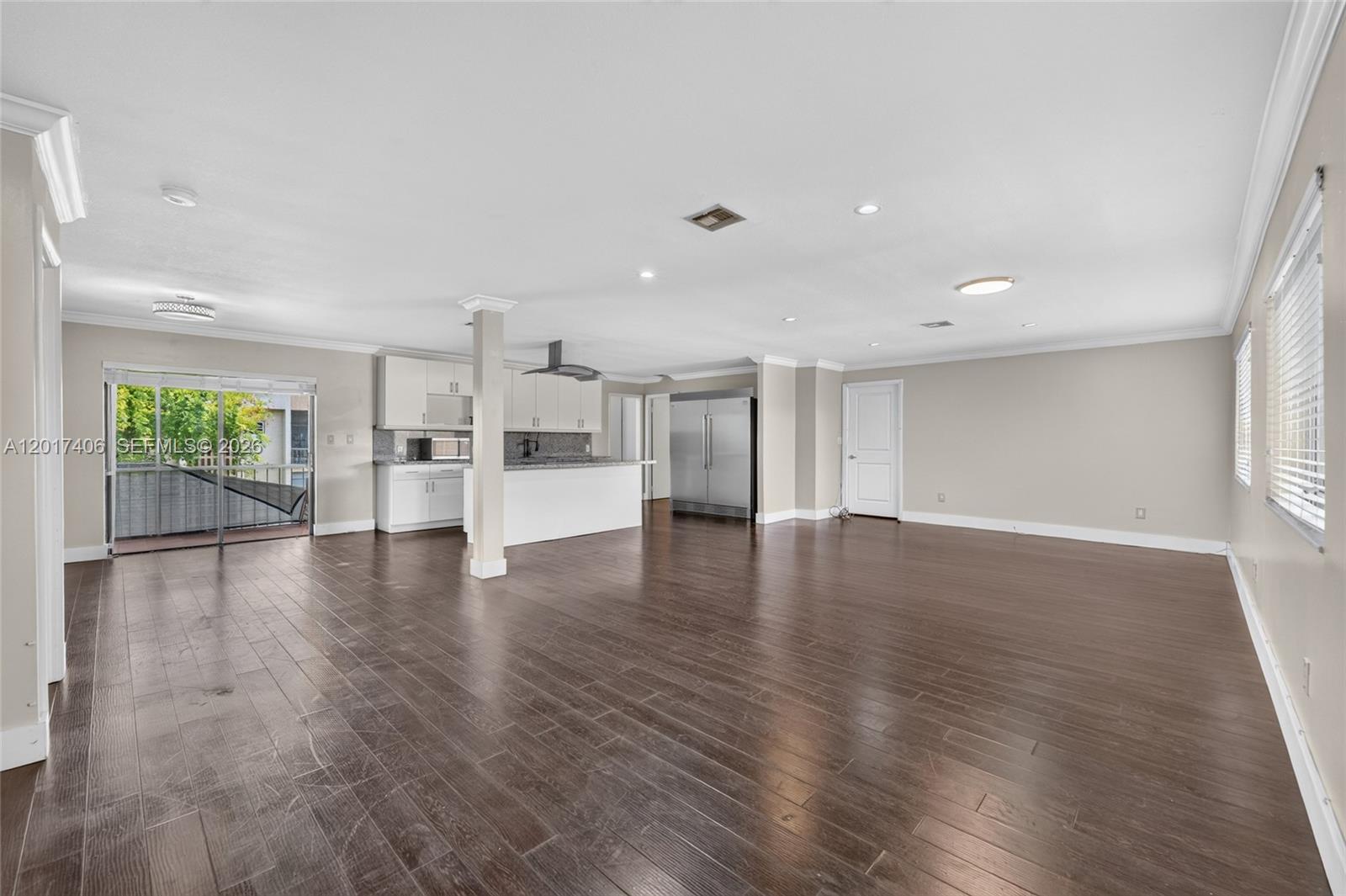 An open-concept living area features dark wood flooring, a kitchen with white cabinets, and a balcony — 8401 SW 107th Ave # 316E, Miami FL 33173, MIAMI, FL