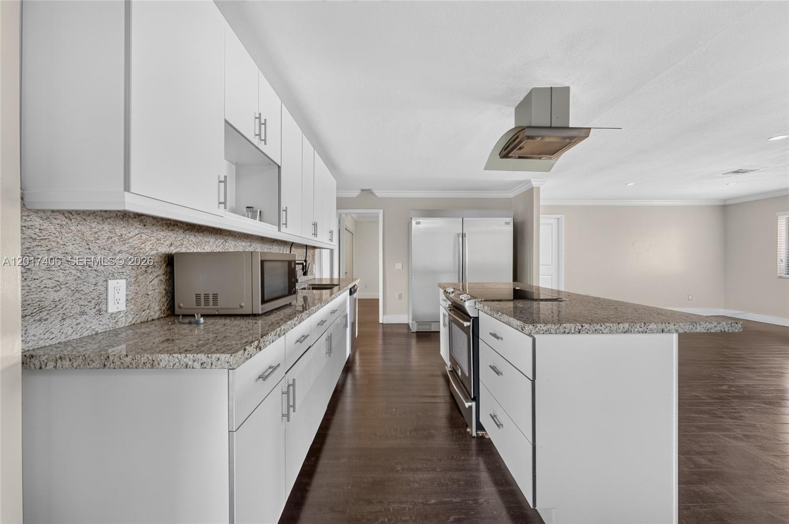 A kitchen features white cabinetry, granite countertops, stainless steel appliances, and dark wood flooring — 8401 SW 107th Ave # 316E, Miami FL 33173, MIAMI, FL
