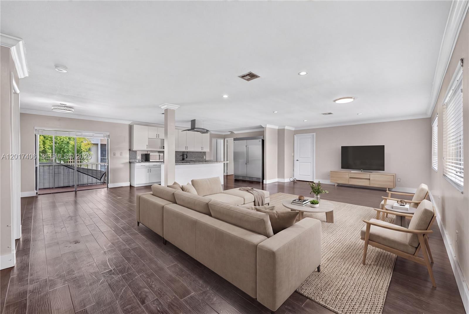 An open-concept living room and kitchen featuring wood flooring, neutral furniture, and a balcony — 8401 SW 107th Ave # 316E, Miami FL 33173, MIAMI, FL