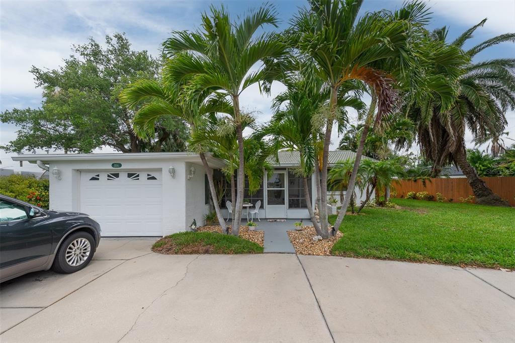 A single-story white house with a garage, a screened front porch, and several palm trees — 55A DOLPHIN DRIVE, TREASURE ISLAND, FL