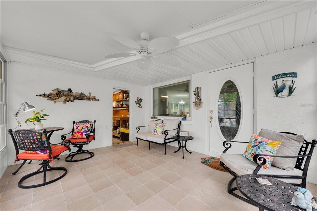A bright, tiled sunroom features a ceiling fan, white walls, and various patio-style furniture — 55A DOLPHIN DRIVE, TREASURE ISLAND, FL