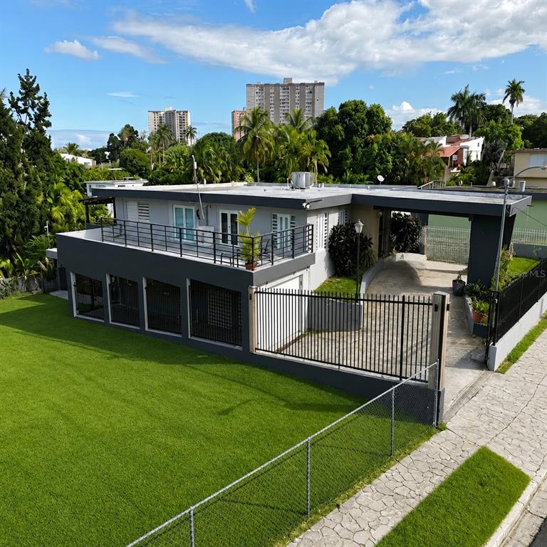 An elevated view of a modern gray house with a flat roof, balcony, and fenced yard — 30 SAN AGUSTIN, SAN JUAN, PR