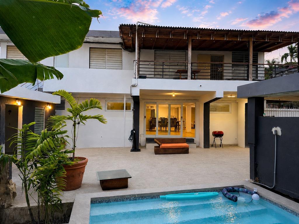 A two-story house with a balcony, patio, and swimming pool at dusk — 30 SAN AGUSTIN, SAN JUAN, PR