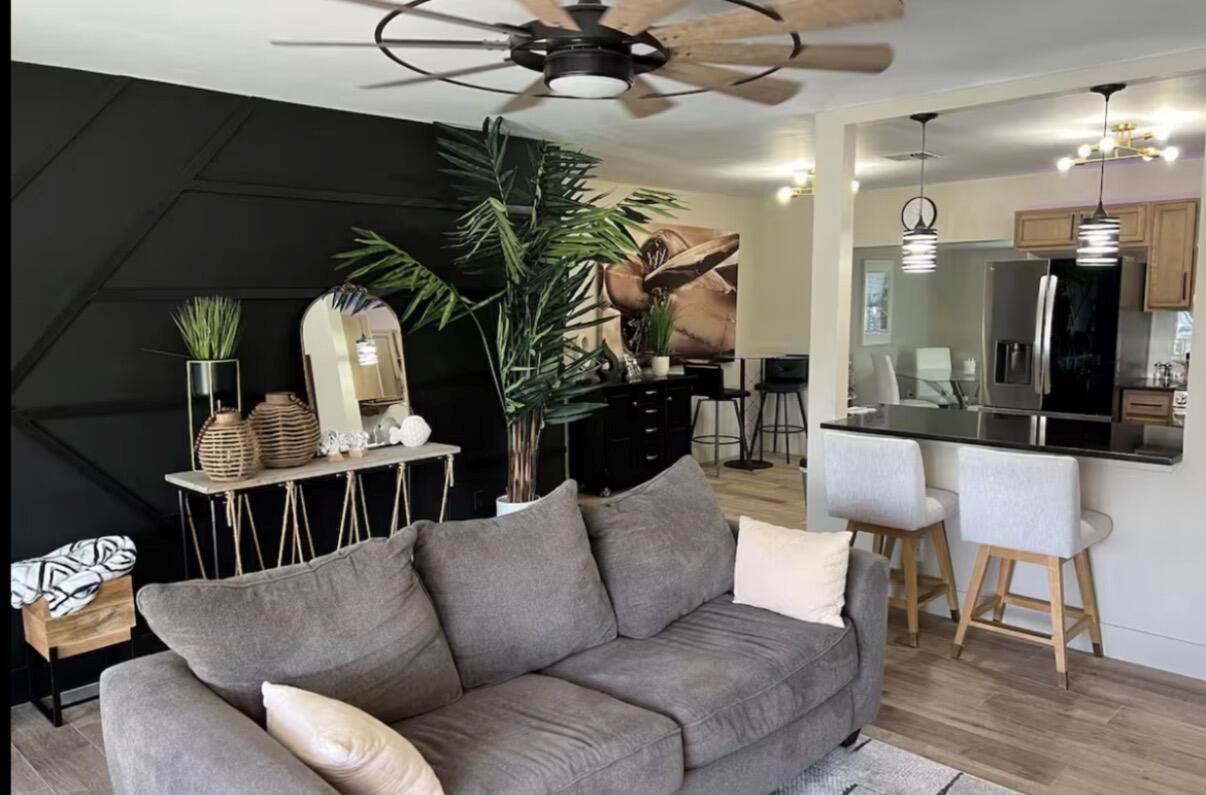 A living room with a black accent wall, gray sofa, and an open kitchen area — 511 SE 5th Street SE, Pompano Beach FL 33060, POMPANO BEACH, FL