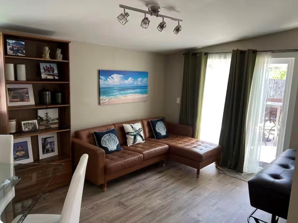 A living room features a brown leather sectional, a bookshelf, and a sliding glass door — 511 SE 5th Street SE, Pompano Beach FL 33060, POMPANO BEACH, FL
