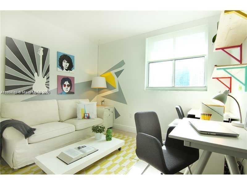 A living room features a white sofa, a coffee table, and a desk with chairs — 1250 S Miami Ave # 901, Miami FL 33130, MIAMI, FL