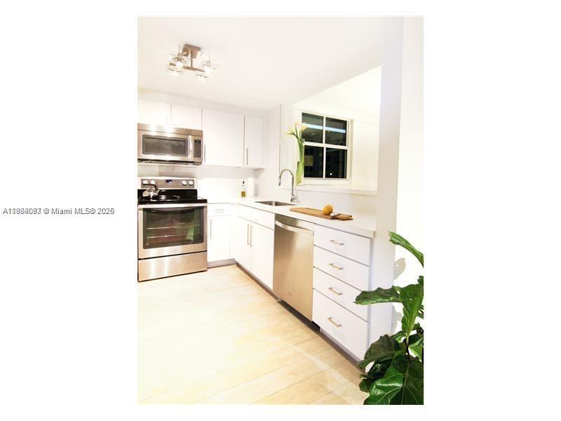 A kitchen with white cabinets, stainless steel appliances, and light wood-look flooring — 1250 S Miami Ave # 901, Miami FL 33130, MIAMI, FL