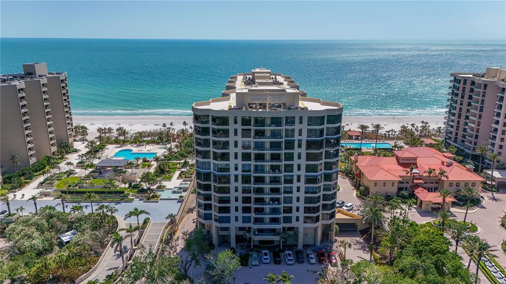 An aerial view of a beachfront condominium complex with a swimming pool and landscaped grounds — 1241 GULF OF MEXICO DRIVE UNIT 603, LONGBOAT KEY, FL