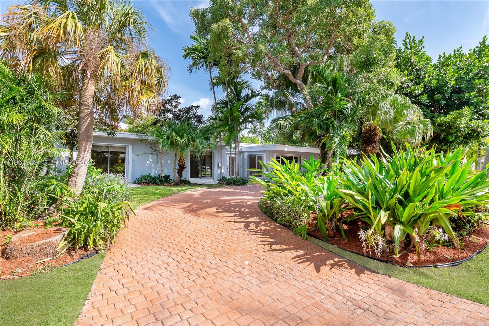 A paved driveway leads to the entrance of a single-story house surrounded by lush landscaping — 310 Harbor Ct, Key Biscayne FL 33149, KEY BISCAYNE, FL