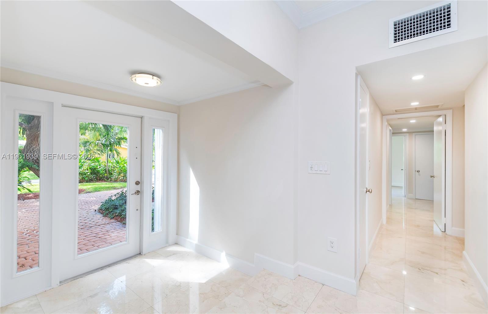 A bright entryway features white walls, marble tile flooring, and a glass-paneled front door — 310 Harbor Ct, Key Biscayne FL 33149, KEY BISCAYNE, FL