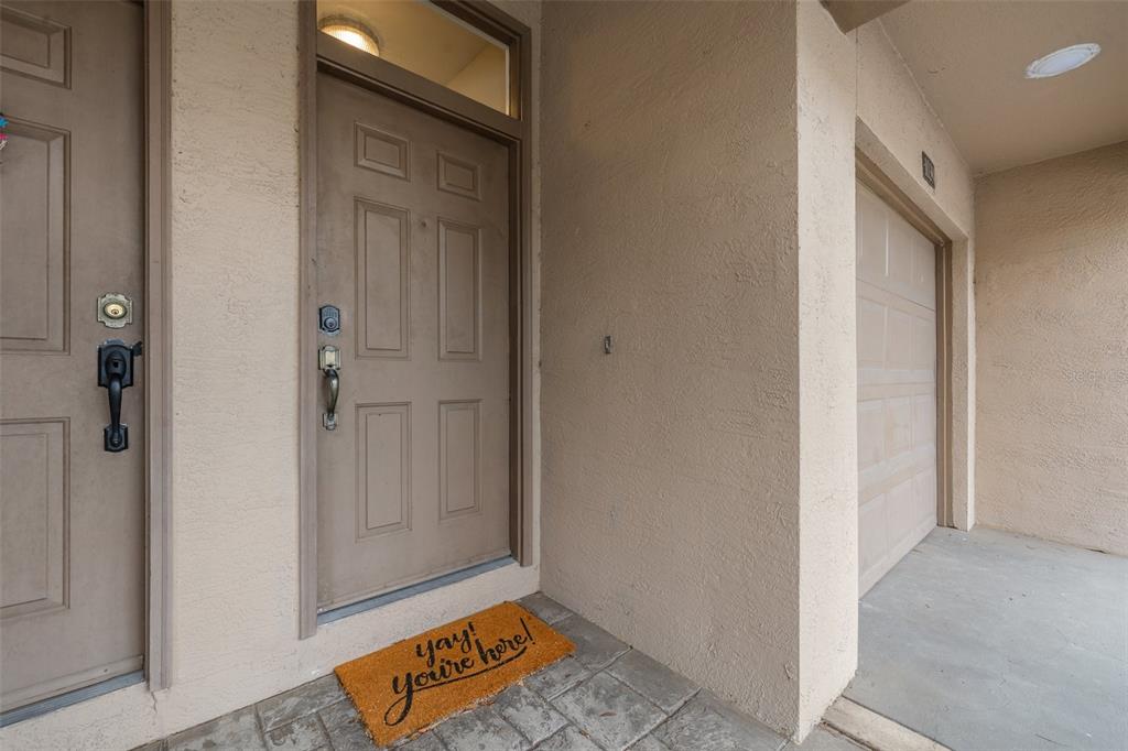 An exterior view of a residential entryway featuring a front door, a garage, and a doormat — 1039 NORMANDY TRACE ROAD UNIT 1039, TAMPA, FL