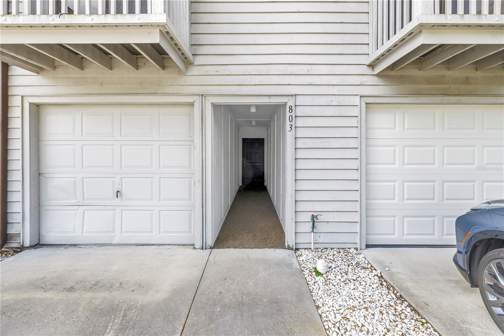 A ground-level view shows two white garage doors flanking a central entryway with number 803 — 6462 92ND PLACE N UNIT 803, PINELLAS PARK, FL