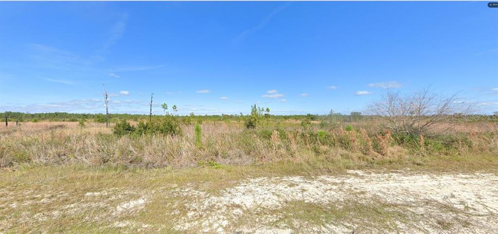 A wide, flat, undeveloped grassy lot under a clear blue sky — 502 PORTULACA DRIVE, INDIAN LAKE ESTATES, FL