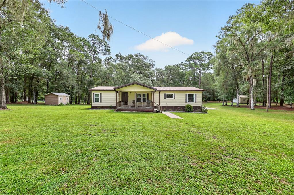 A single-story house with light yellow siding and a front porch sits on a grassy lot — 7727 CR 659, BUSHNELL, FL