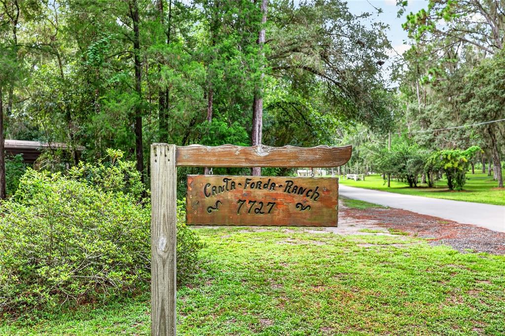 A wooden sign for Canta-Forda Ranch stands on a post beside a paved road — 7727 CR 659, BUSHNELL, FL