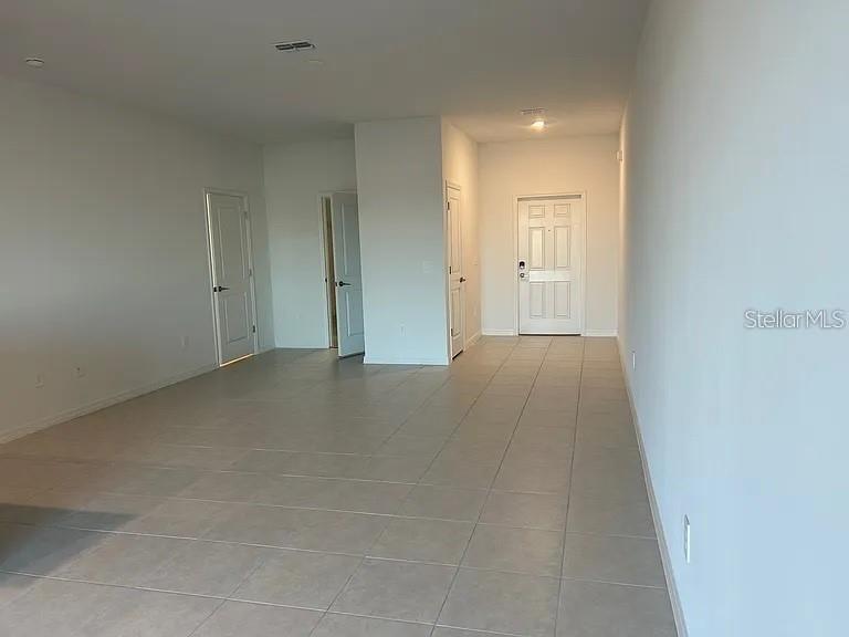 An empty room with light-colored tile flooring, white walls, and several interior doors — 11324 65TH TERRACE E, PALMETTO, FL