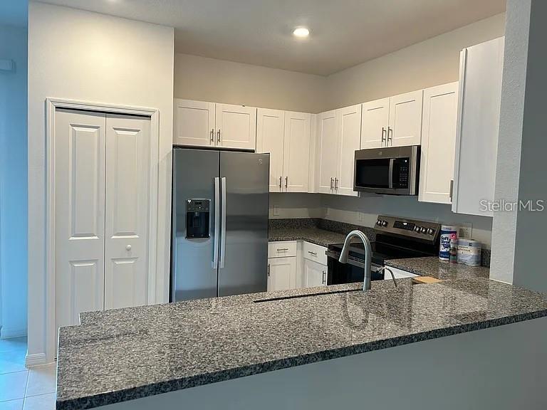 A kitchen features white cabinets, stainless steel appliances, and a granite-topped breakfast bar — 11324 65TH TERRACE E, PALMETTO, FL