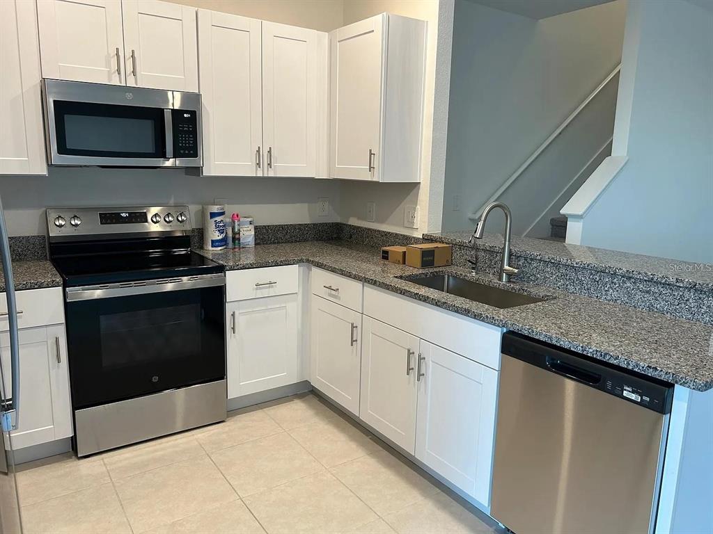 A kitchen features white cabinets, granite countertops, and stainless steel appliances — 11324 65TH TERRACE E, PALMETTO, FL