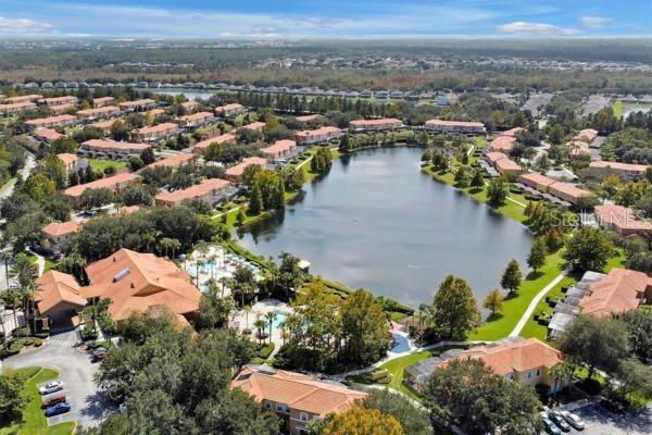 An aerial view of a residential community featuring a central lake and swimming pool area — 3045 YELLOW LANTANA LANE, KISSIMMEE, FL