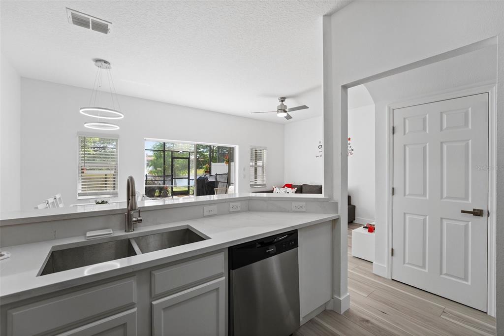 A kitchen sink and dishwasher overlook a living area with a view of a patio — 3045 YELLOW LANTANA LANE, KISSIMMEE, FL